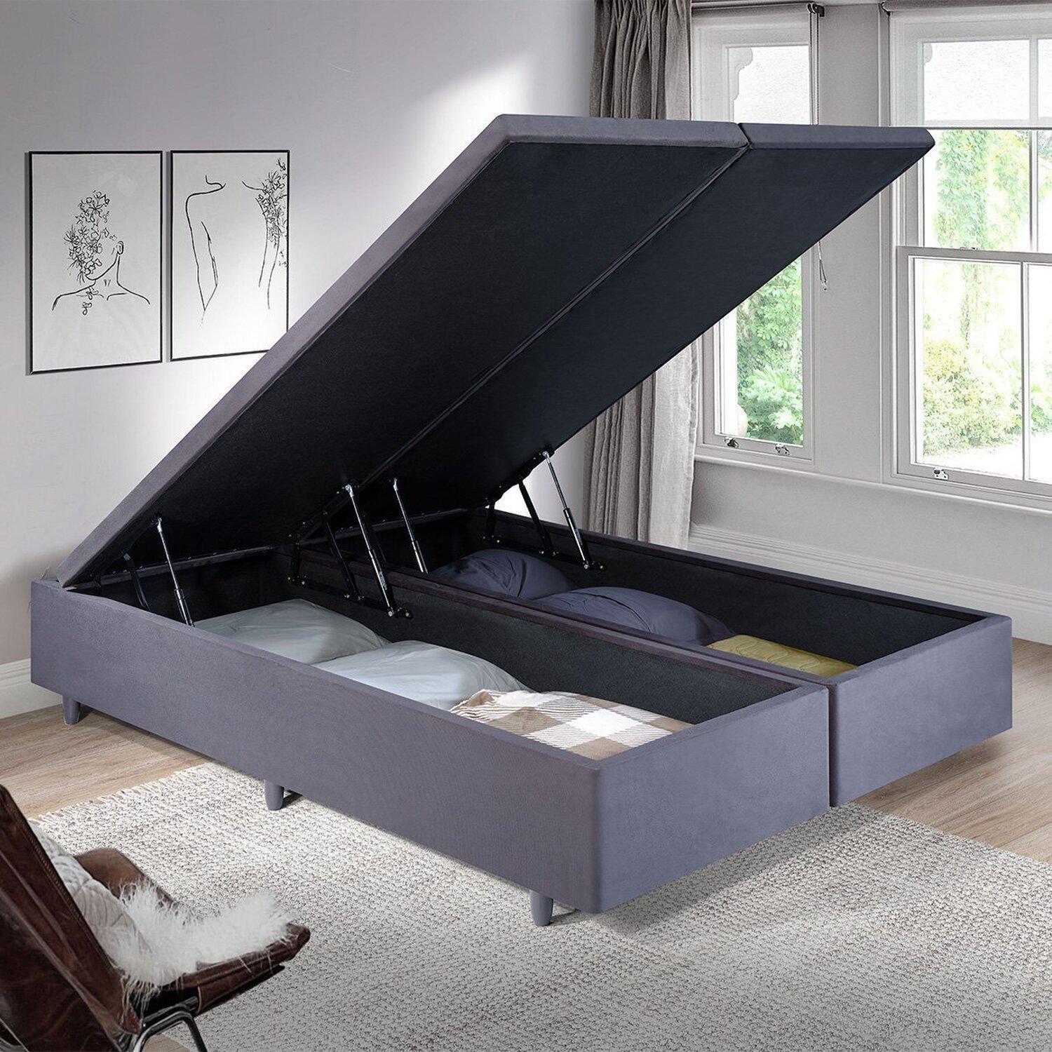 Base cama dividida tapizada en color gris oscuro con patas de madera en un dormitorio moderno.